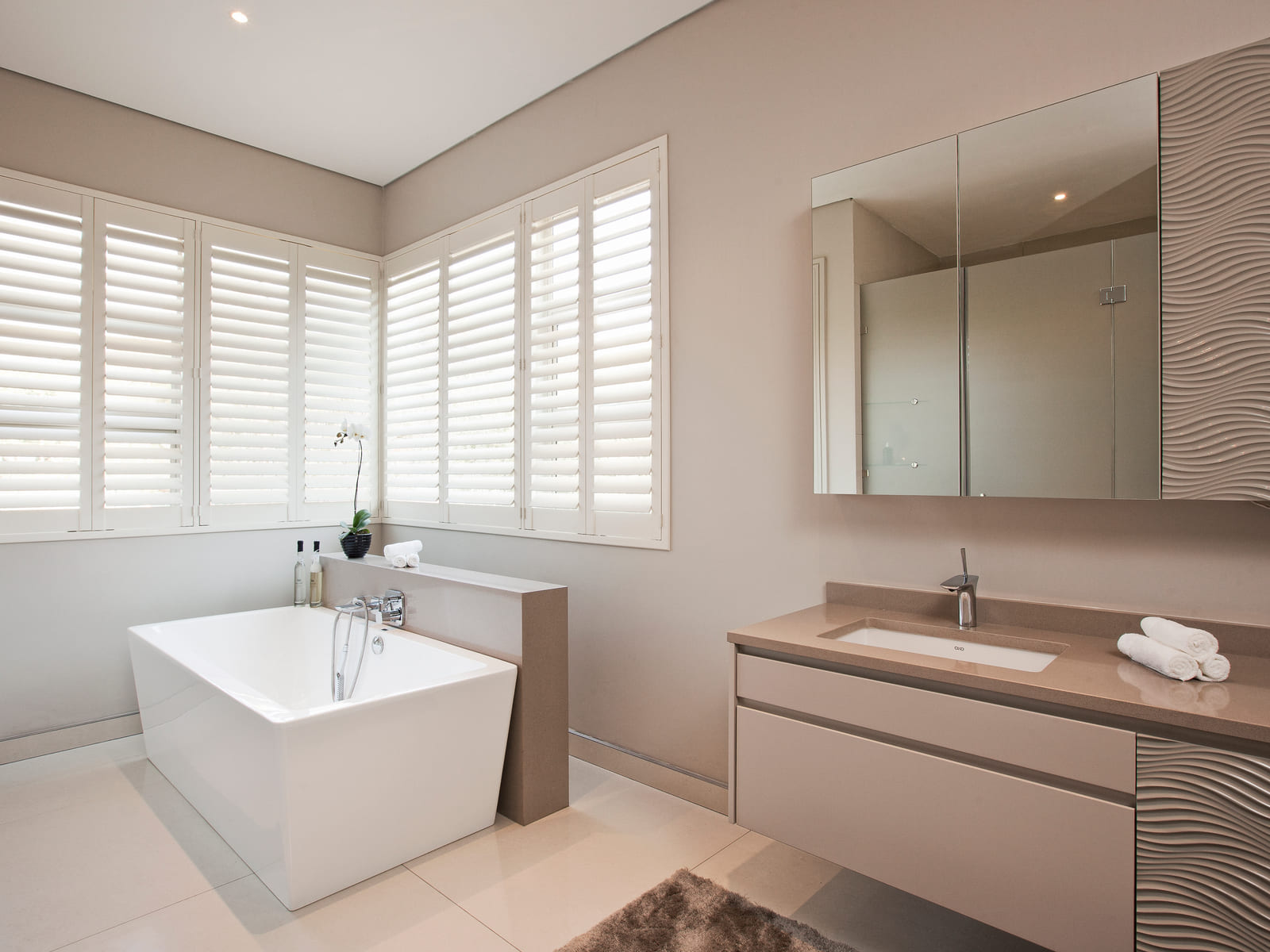 Stone-clad master en-suite with freestanding bath and layered lighting