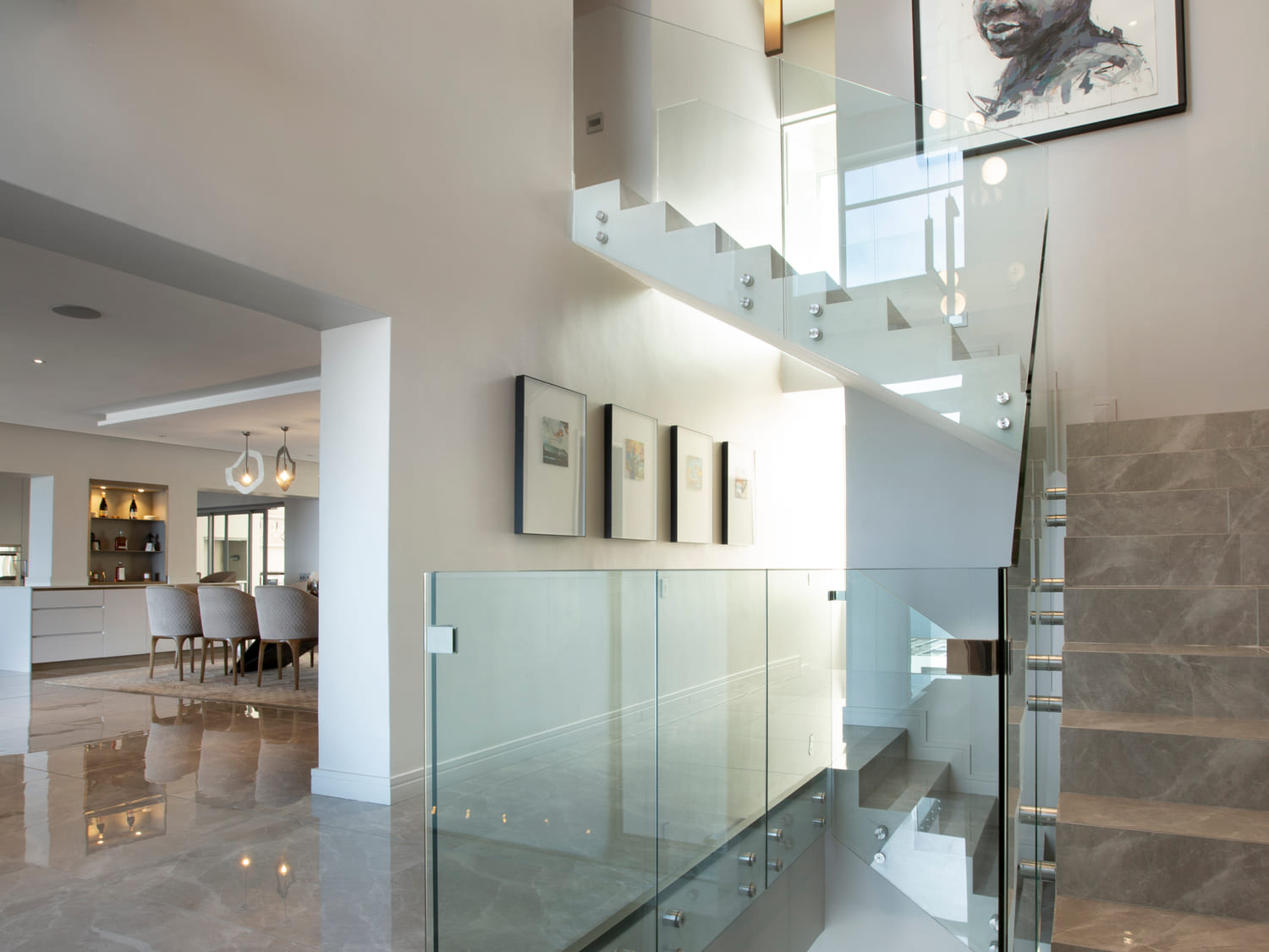 Staircase and entrance hall with glass balustrade and art